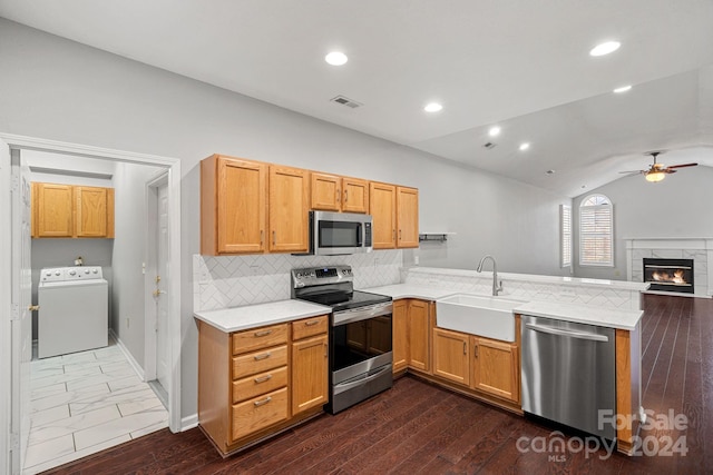 kitchen with stainless steel appliances, vaulted ceiling, sink, washer / dryer, and dark hardwood / wood-style floors