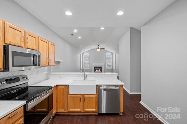 kitchen featuring lofted ceiling, sink, ceiling fan, appliances with stainless steel finishes, and kitchen peninsula