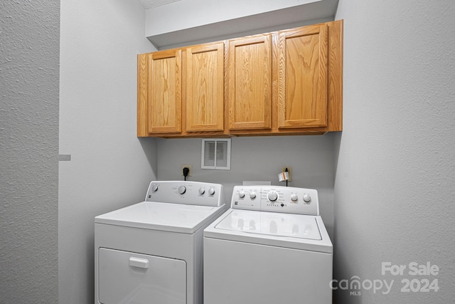 laundry area with washer and clothes dryer and cabinets