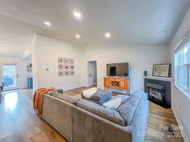living room featuring light wood-type flooring, recessed lighting, baseboards, and vaulted ceiling