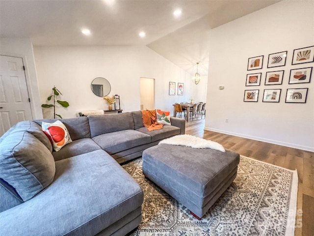 living room with wood finished floors, baseboards, lofted ceiling, an inviting chandelier, and recessed lighting