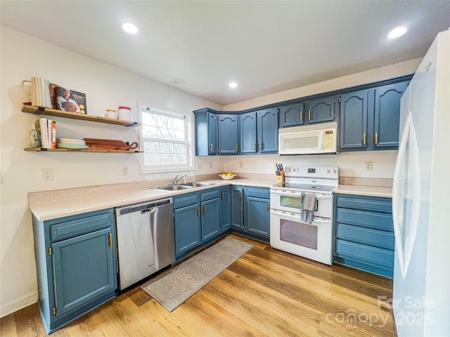 kitchen featuring white appliances, light countertops, a sink, light wood finished floors, and blue cabinetry