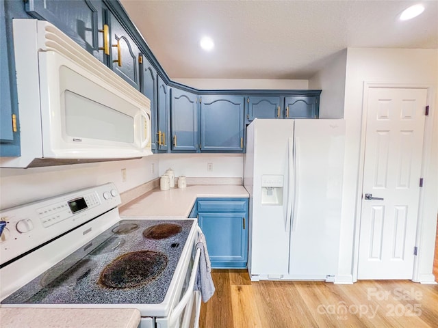 kitchen with blue cabinets, light wood-type flooring, light countertops, recessed lighting, and white appliances