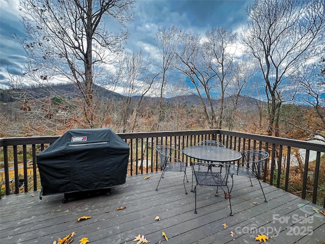 wooden terrace featuring area for grilling, a mountain view, and outdoor dining space