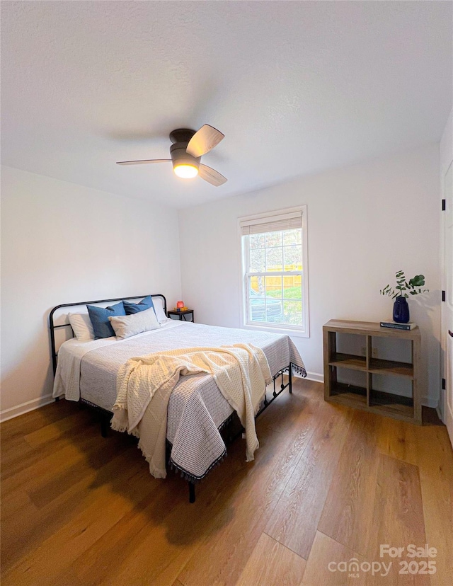 bedroom with light wood-style floors, baseboards, and a ceiling fan