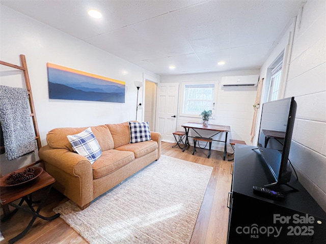 living room featuring an AC wall unit, recessed lighting, and light wood-style flooring