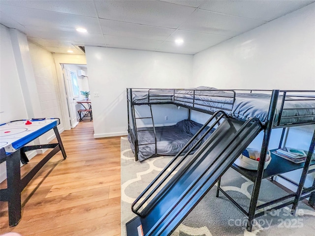 bedroom with recessed lighting, baseboards, light wood-type flooring, and a paneled ceiling