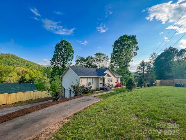 view of front facade with fence, an attached garage, driveway, and a front yard