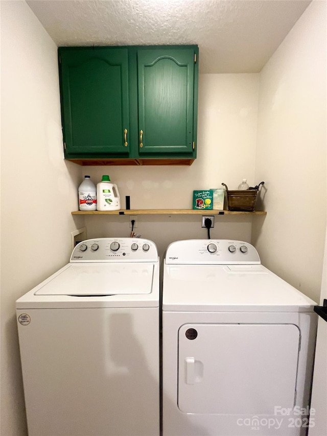 clothes washing area featuring separate washer and dryer, a textured ceiling, and cabinet space