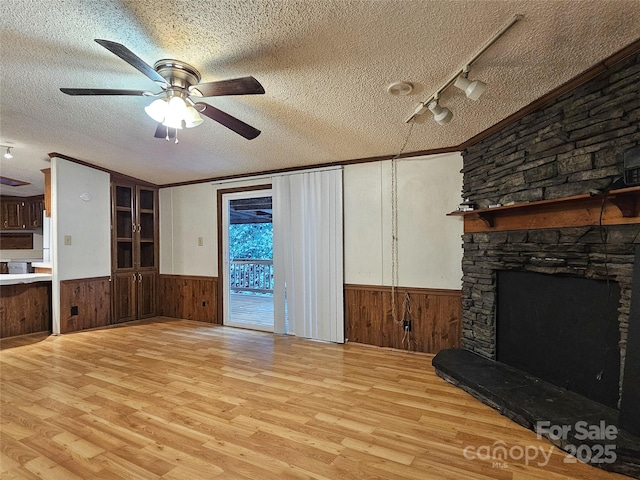 living room featuring ceiling fan, light wood-type flooring, a fireplace, and a textured ceiling