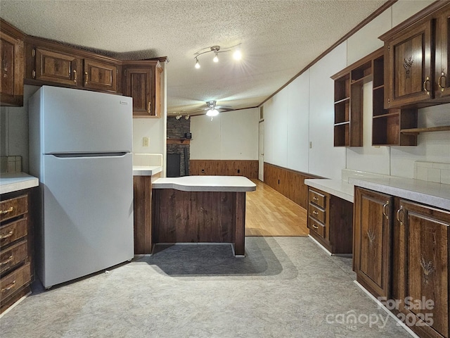 kitchen with crown molding, dark brown cabinetry, refrigerator, and a textured ceiling