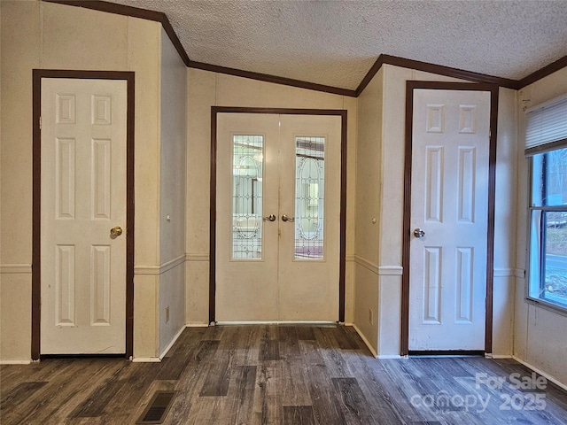 foyer with crown molding, lofted ceiling, dark hardwood / wood-style floors, and a textured ceiling