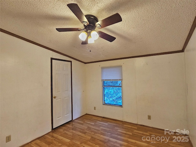 unfurnished room featuring crown molding, ceiling fan, a textured ceiling, vaulted ceiling, and light wood-type flooring