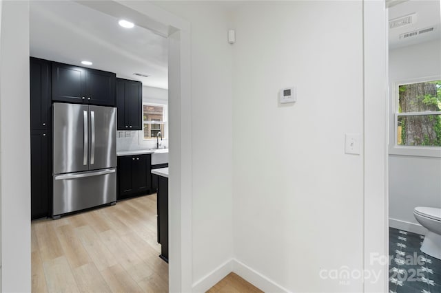kitchen with a sink, light countertops, freestanding refrigerator, and dark cabinets