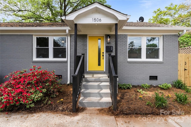 view of front of home featuring brick siding, crawl space, and fence