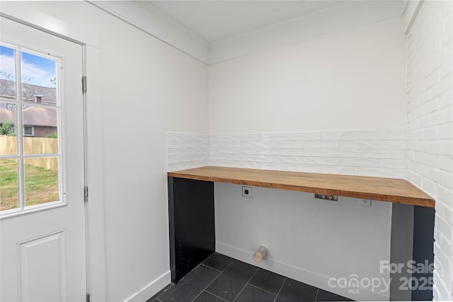 interior space featuring dark tile patterned flooring, a healthy amount of sunlight, crown molding, and baseboards