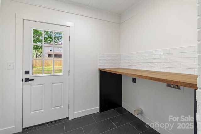 doorway to outside featuring dark tile patterned floors, ornamental molding, and baseboards