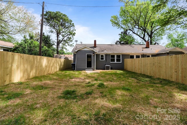 rear view of property with central AC unit, a fenced backyard, and a lawn