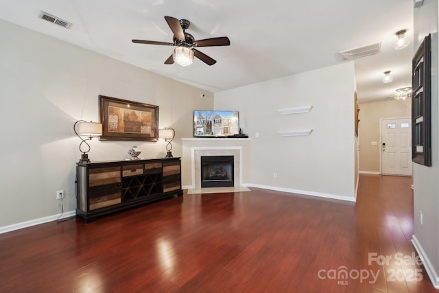 living area featuring a fireplace, visible vents, and wood finished floors