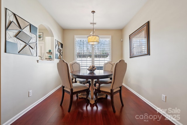 dining space featuring visible vents, baseboards, arched walkways, and dark wood-type flooring