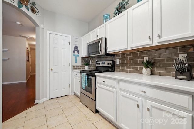 kitchen featuring light tile patterned floors, white cabinets, light countertops, appliances with stainless steel finishes, and tasteful backsplash