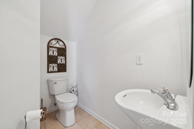 bathroom featuring toilet, baseboards, a sink, and tile patterned floors