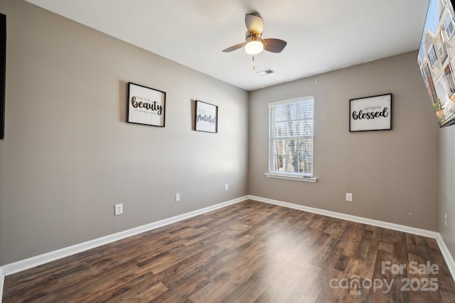 spare room featuring ceiling fan, dark wood finished floors, and baseboards