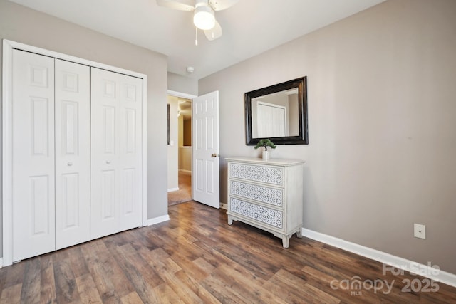 unfurnished bedroom with a closet, wood finished floors, a ceiling fan, and baseboards