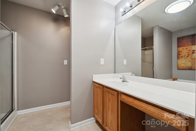 full bath featuring a shower stall, vanity, and baseboards