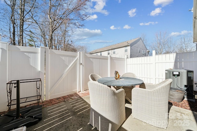 view of patio / terrace featuring a gate, outdoor dining area, a fenced backyard, and central air condition unit