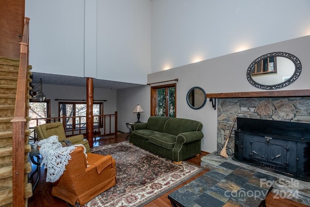 living room with a fireplace, dark hardwood / wood-style flooring, and a towering ceiling