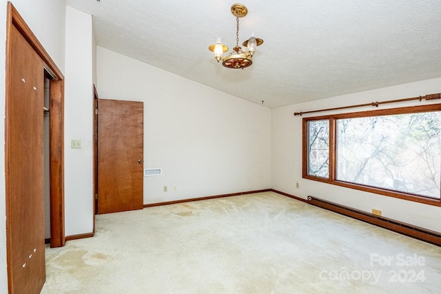 carpeted spare room featuring a chandelier, a textured ceiling, and vaulted ceiling