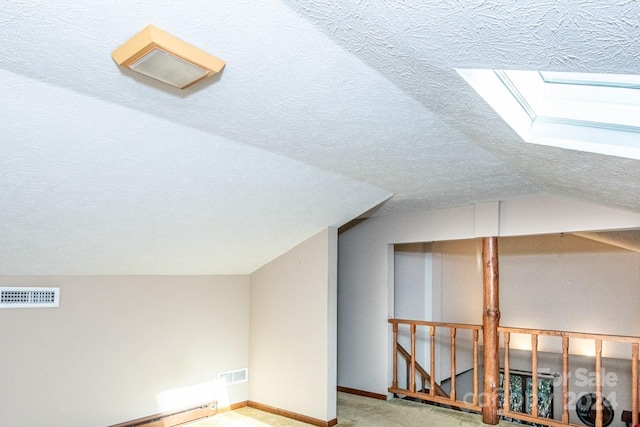 additional living space featuring carpet flooring, a textured ceiling, lofted ceiling with skylight, and baseboard heating