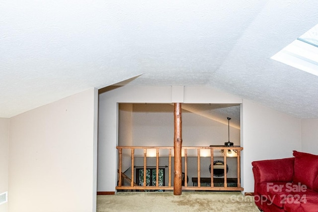 additional living space featuring a textured ceiling, carpet floors, and lofted ceiling with skylight