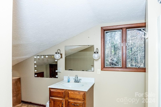 bathroom featuring a textured ceiling, vanity, and vaulted ceiling