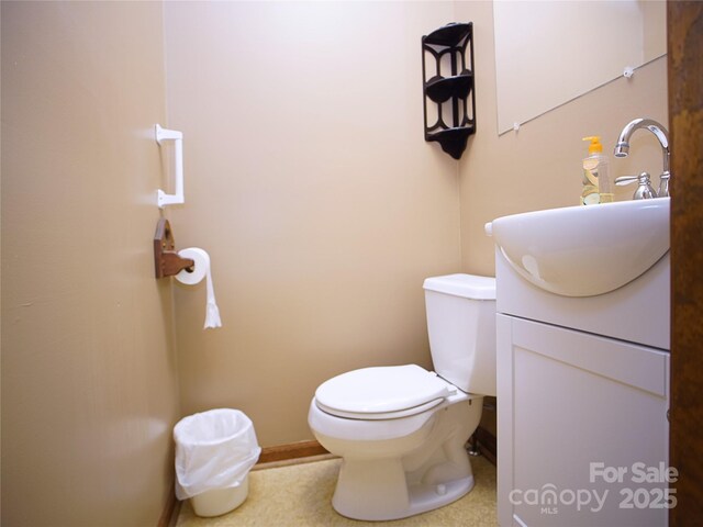 half bathroom featuring toilet, baseboards, and vanity