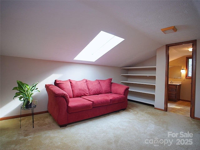 living room with vaulted ceiling with skylight, baseboards, and carpet flooring