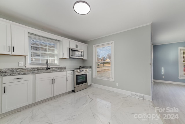 kitchen featuring light stone countertops, white cabinets, ornamental molding, and appliances with stainless steel finishes