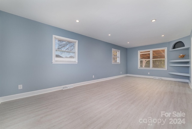 spare room with built in shelves and light wood-type flooring