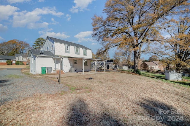 rear view of property with cooling unit, a patio area, and a shed