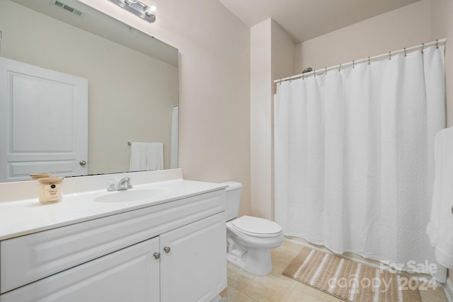 bathroom with toilet, vanity, and tile patterned floors