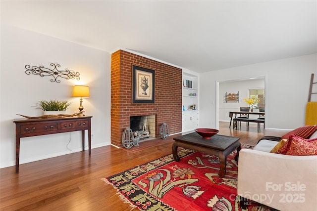 living room with hardwood / wood-style flooring, built in features, and a fireplace