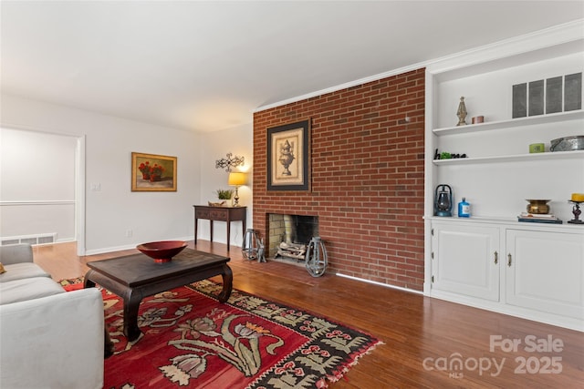 living room with brick wall, a brick fireplace, and dark hardwood / wood-style floors