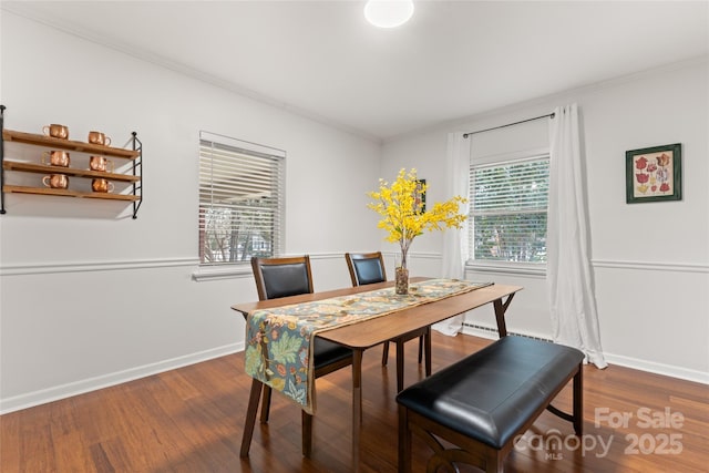 dining area with ornamental molding and dark hardwood / wood-style flooring