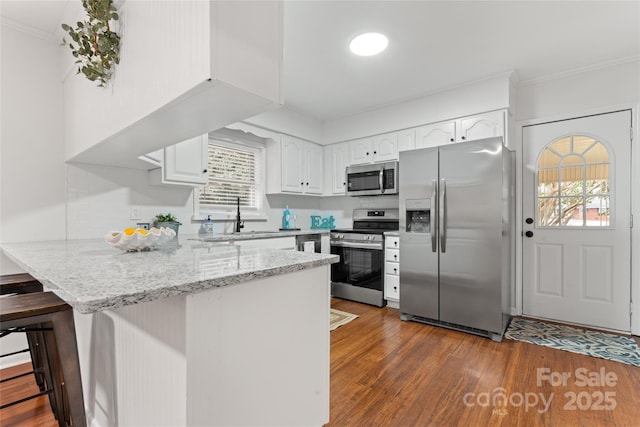 kitchen with sink, a breakfast bar area, white cabinets, kitchen peninsula, and stainless steel appliances