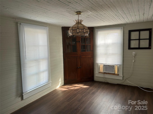 unfurnished dining area featuring cooling unit, plenty of natural light, wooden ceiling, and dark hardwood / wood-style floors