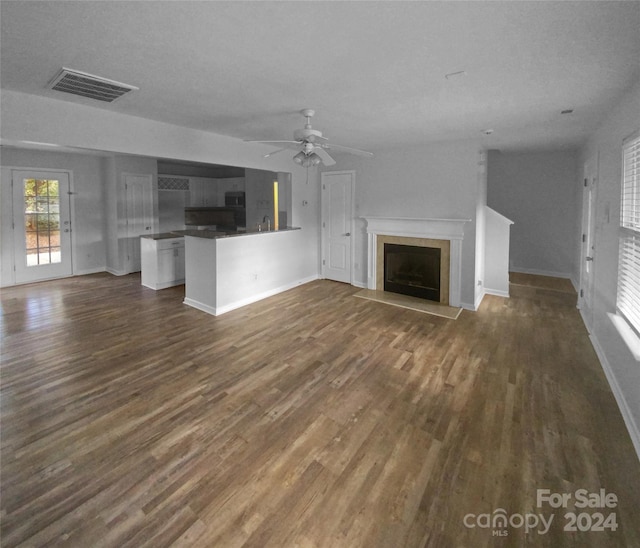 unfurnished living room featuring a textured ceiling, ceiling fan, and dark hardwood / wood-style floors