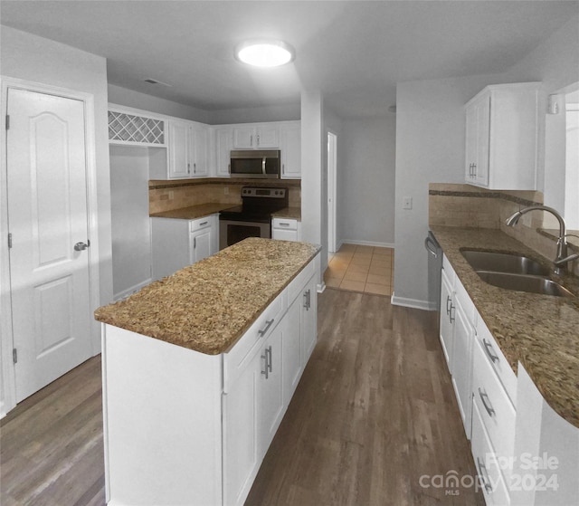 kitchen with appliances with stainless steel finishes, dark hardwood / wood-style flooring, white cabinetry, and sink