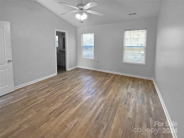 unfurnished bedroom featuring dark wood-type flooring, ensuite bath, multiple windows, and lofted ceiling