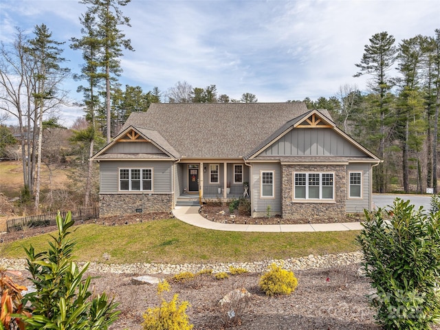 craftsman-style house with board and batten siding, stone siding, covered porch, and a front lawn